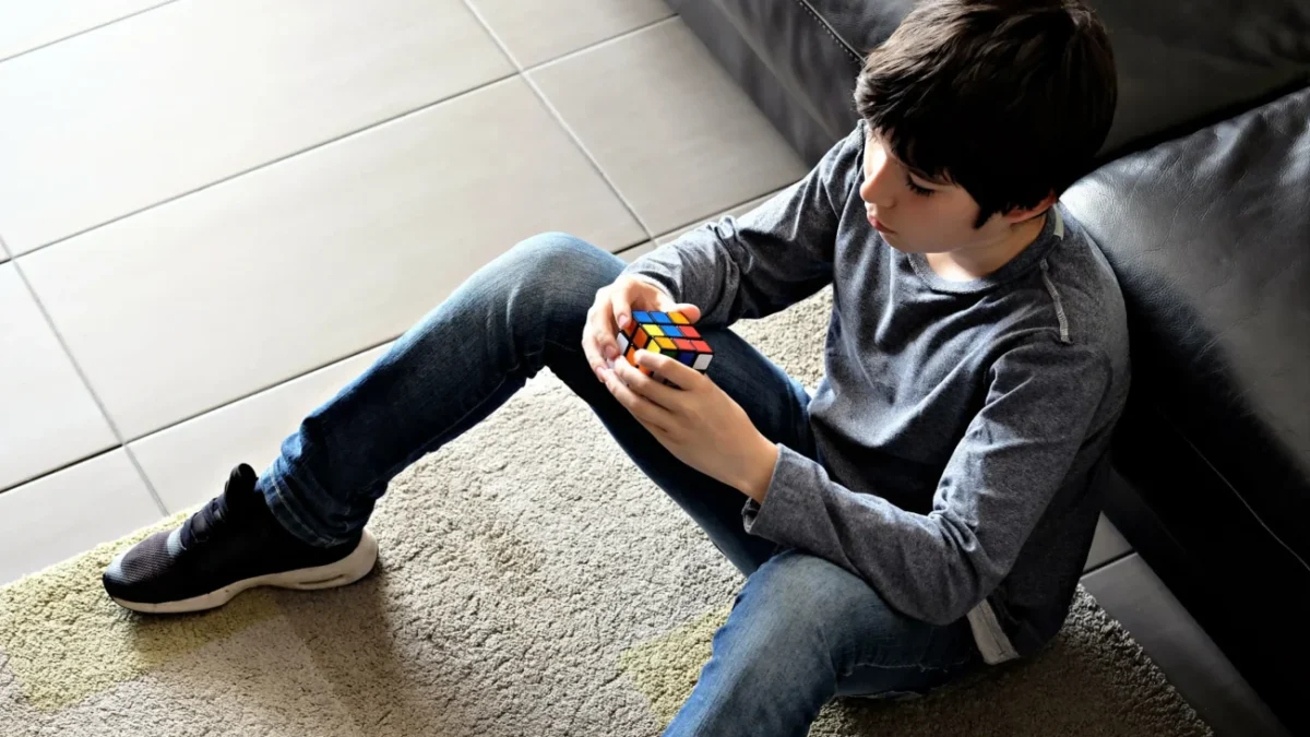 Chlapec sedí na zemi a v ruce drží Rubikovu kostku.