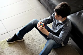 Chlapec sedí na zemi a v ruce drží Rubikovu kostku.