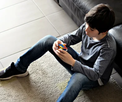 Chlapec sedí na zemi a v ruce drží Rubikovu kostku.