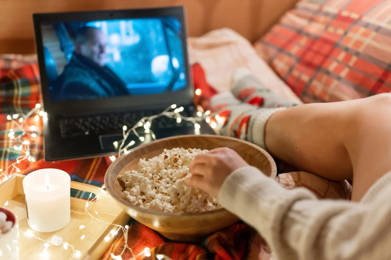 shutterstock_2091598315-2 | TVGURU.cz Žena se dívá v posteli na film a bere si z misky popcorn.