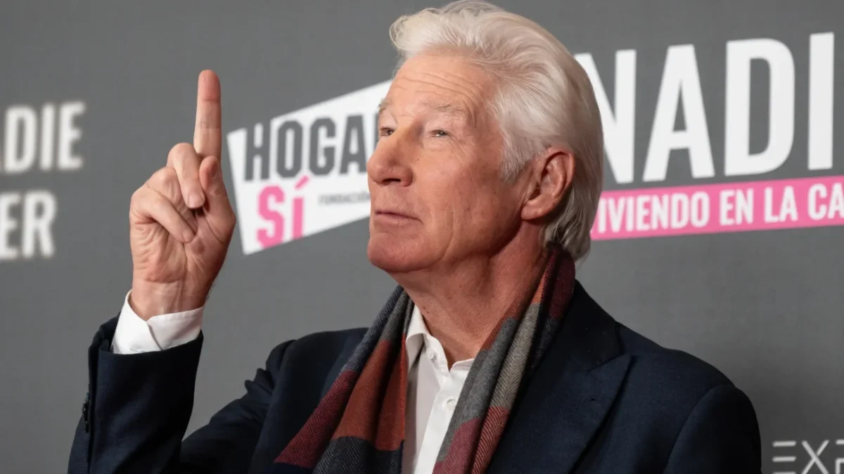 Richard Gere ukazuje prstem nahoru.
