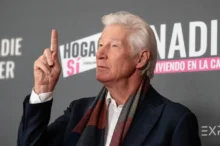 Richard Gere ukazuje prstem nahoru.