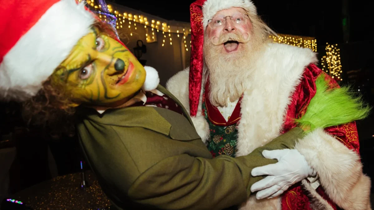 Muži v převleku Grinche a Santa Clause se objímají.