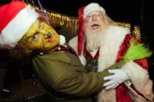 Muži v převleku Grinche a Santa Clause se objímají.