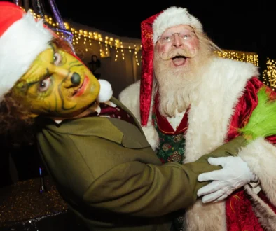 Muži v převleku Grinche a Santa Clause se objímají.