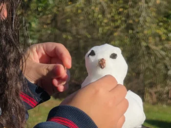 Člověk upravuje sněhuláka.