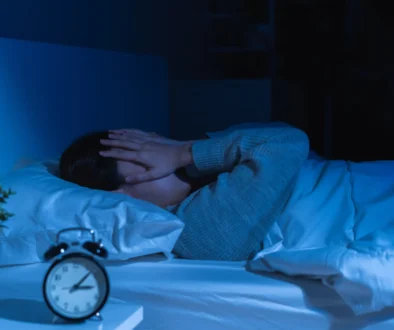 člověk v posteli s rukama na obličeji