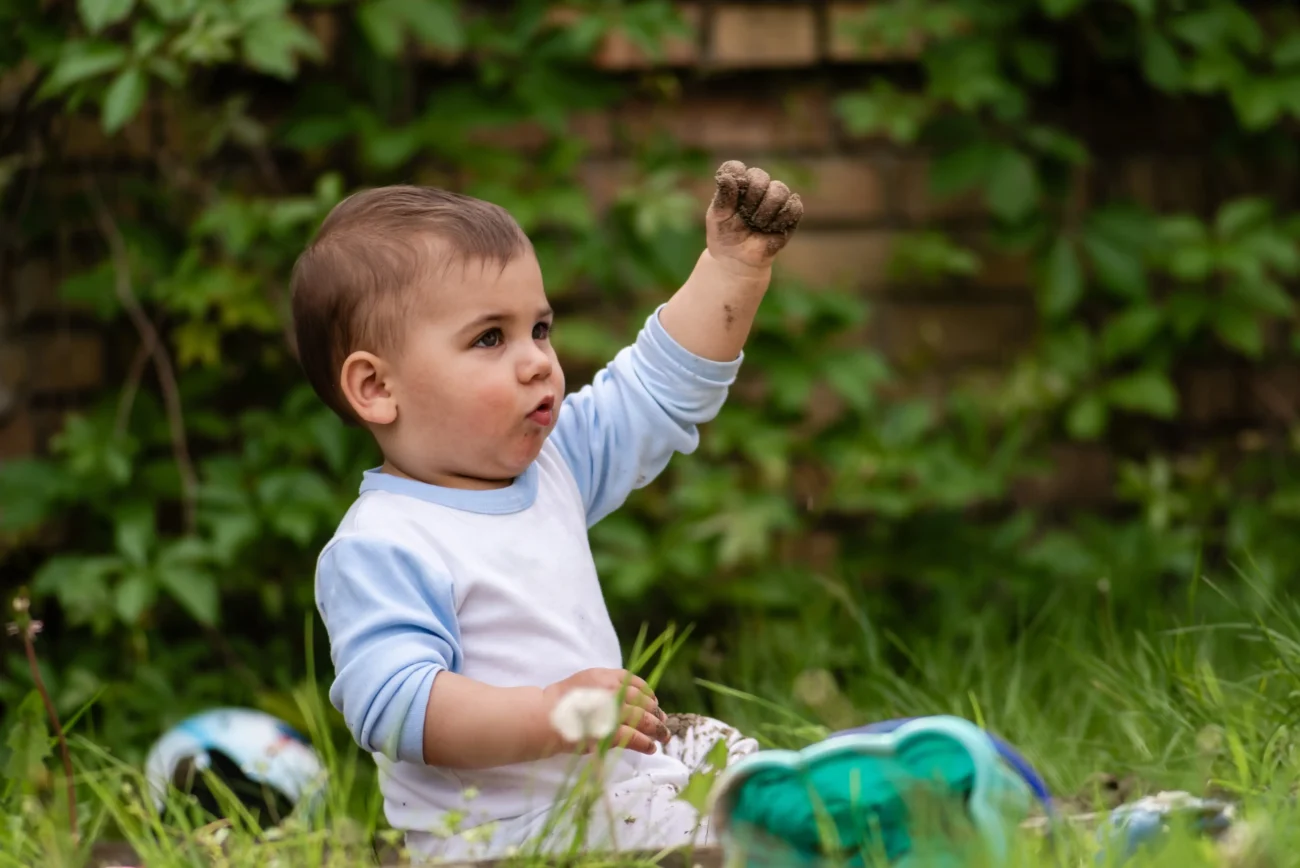 shutterstock_2643588229-2 | TVGURU.cz Chlapeček si na zemi hraje s hlínou.