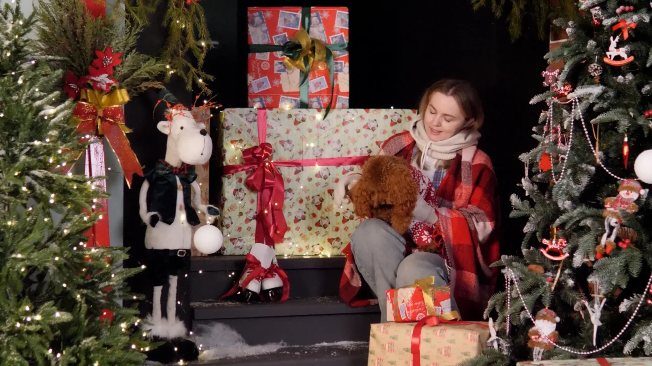 Žena sedí mezi vánočním zdobením. 