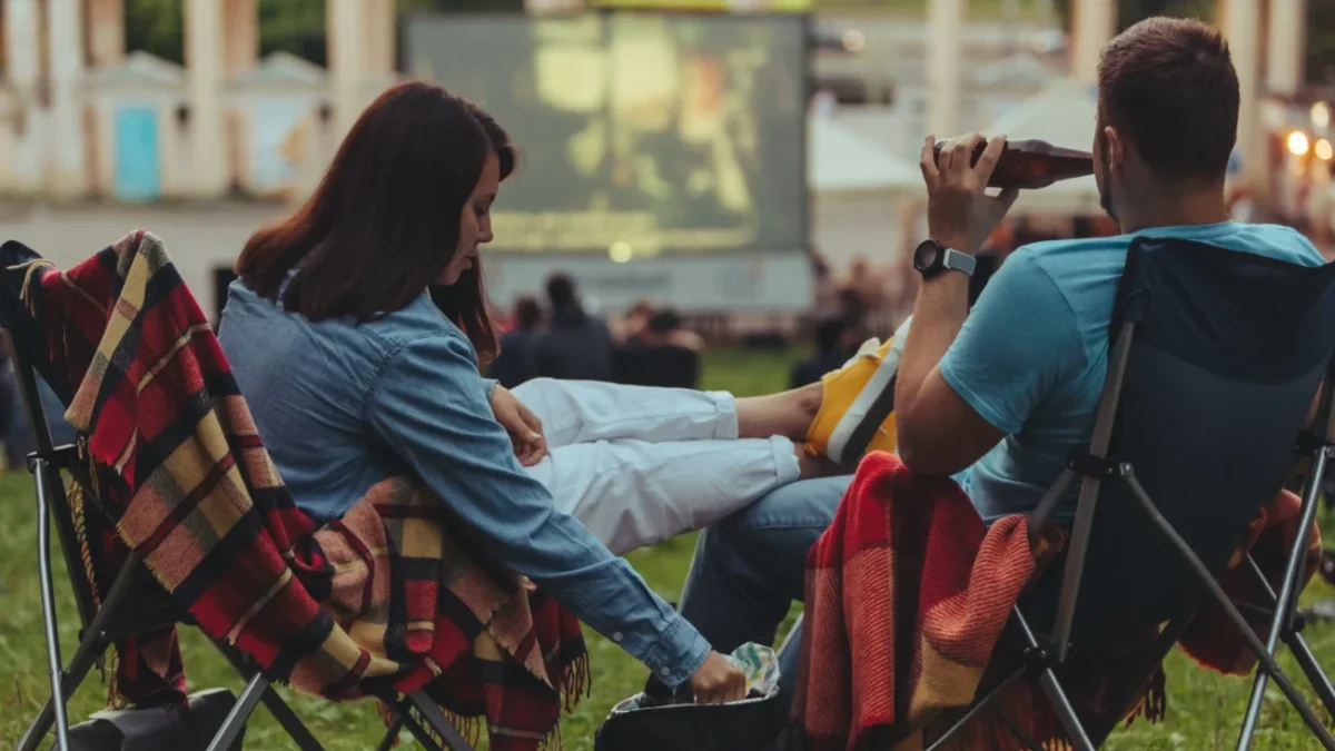 Lidé sedí a sledují letní kino.