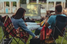 Lidé sedí a sledují letní kino.