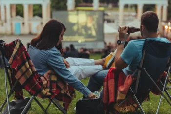 Lidé sedí a sledují letní kino.