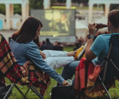 Lidé sedí a sledují letní kino.