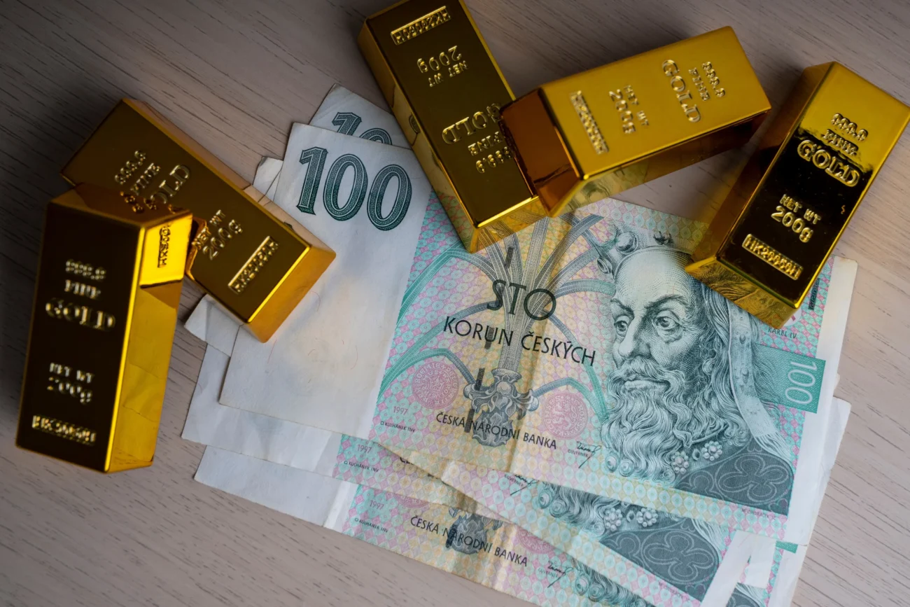 shutterstock_2218953735-2 | TVGURU.cz Na stole leží peníze a zlaté cihly.
