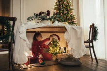 Děti si hrají po vánočně vyzdobeným stolkem.