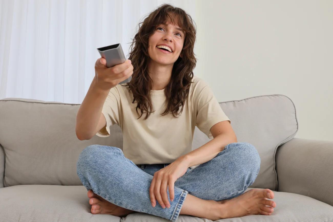 shutterstock_2667259409 | TVGURU.cz Mladá žena sleduje TV