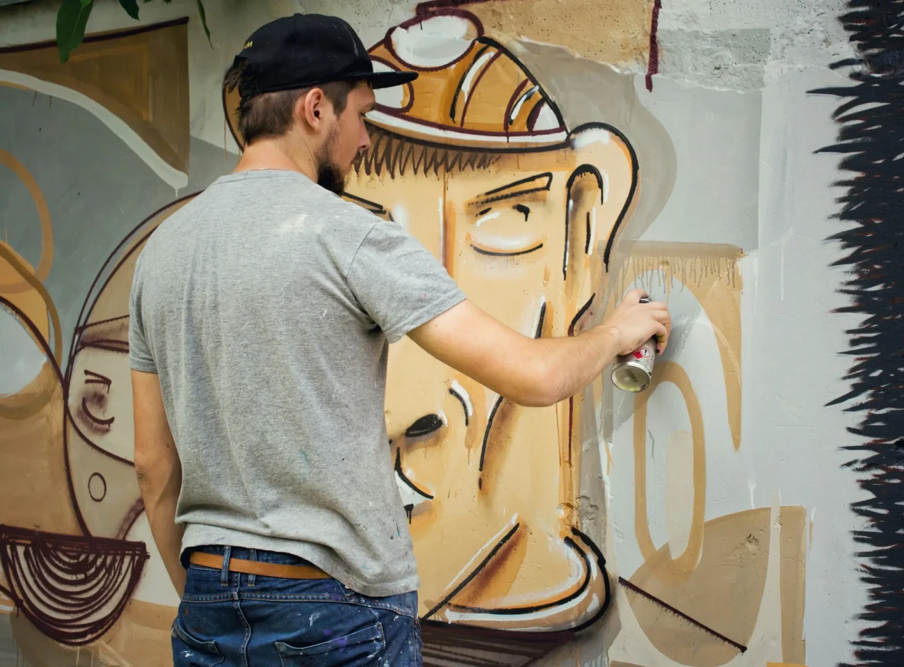 shutterstock_537556399 1 | TVGURU.cz Muž maluje graffity na zeď.