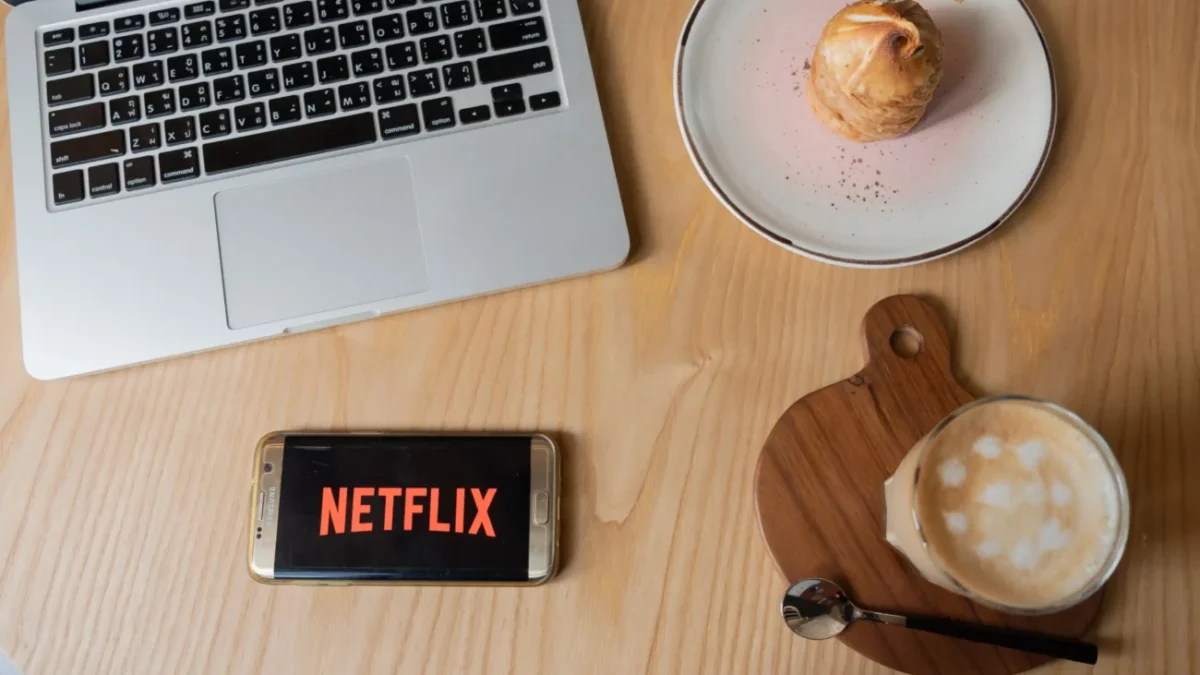 Na stole leží občerstvení a mobil s Netflixem.