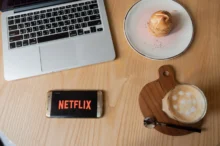 Na stole leží občerstvení a mobil s Netflixem.