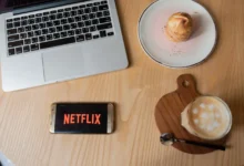 Na stole leží občerstvení a mobil s Netflixem.