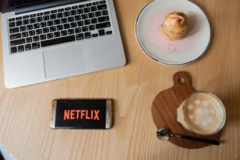 Na stole leží občerstvení a mobil s Netflixem.