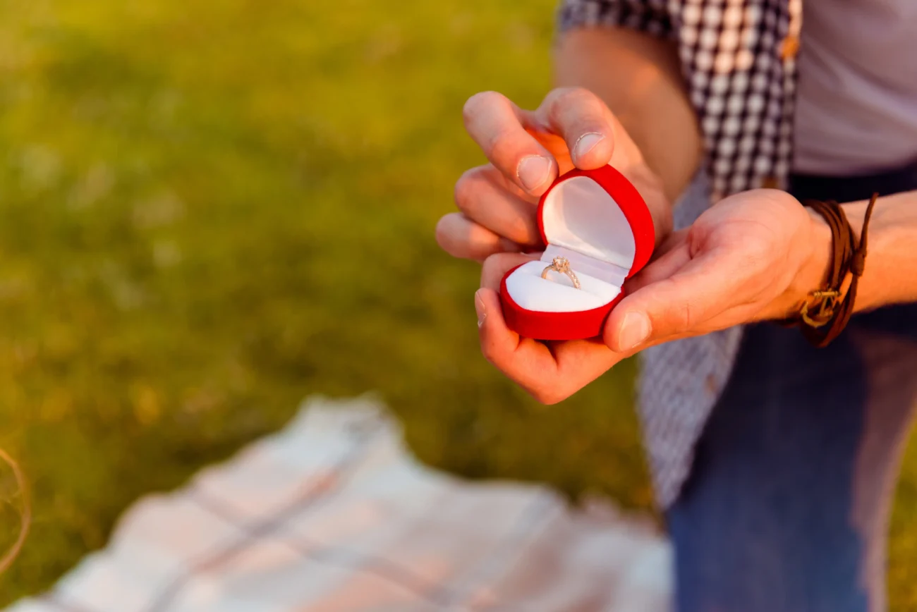 Člověk v ruce drží krabičku s prstýnkem. 