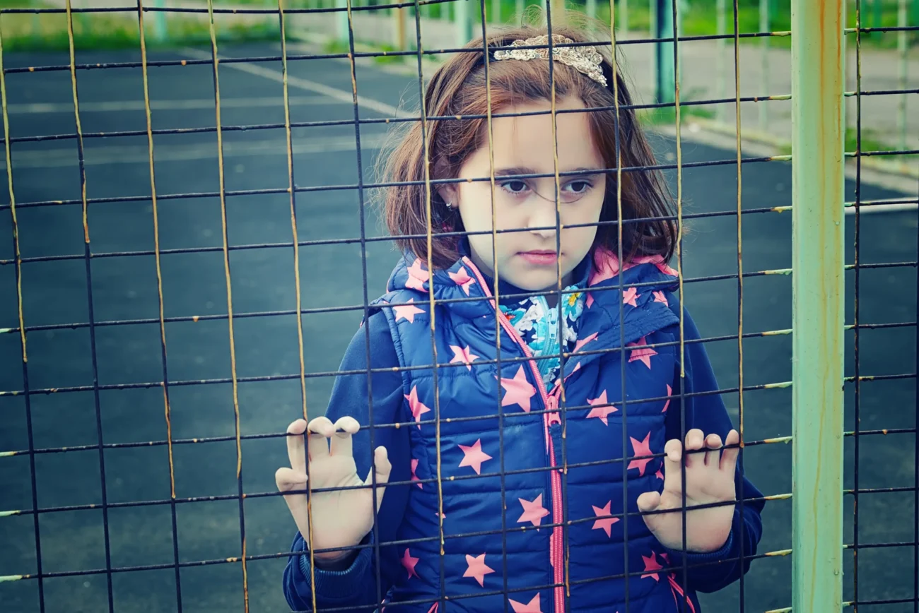 shutterstock_1111477625-2 | TVGURU.cz Holčička stojí za plotem.