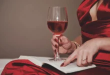 Žena v ruce drží knihu a sklenku s vínem.