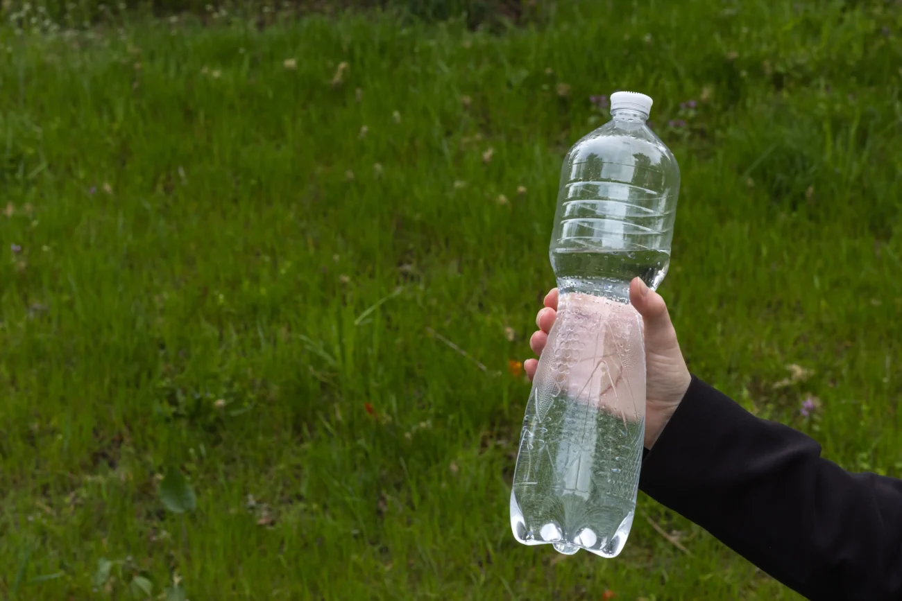Člověk v ruce drží lahev s vodou.