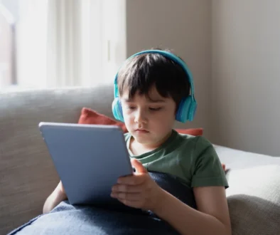 Chlapeček je na tabletu a na uších má sluchátka.