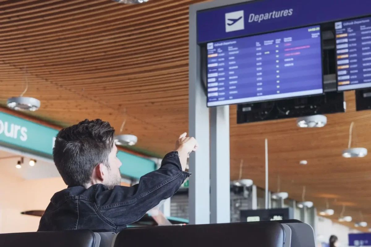 Muž ukazuje na ceduli s odlety.