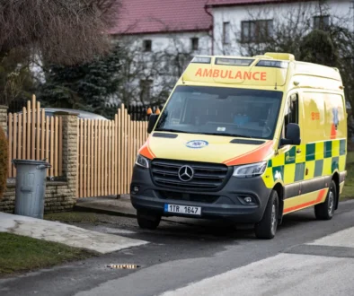 Před plotem stojí sanitka.