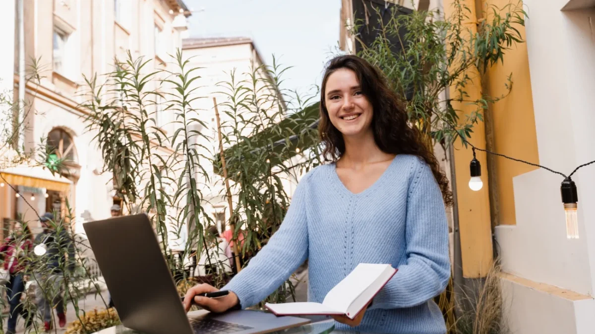 Žena sedí venku u notebooku.