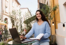 Žena sedí venku u notebooku.
