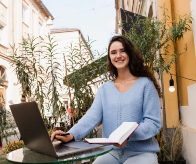 Žena sedí venku u notebooku.