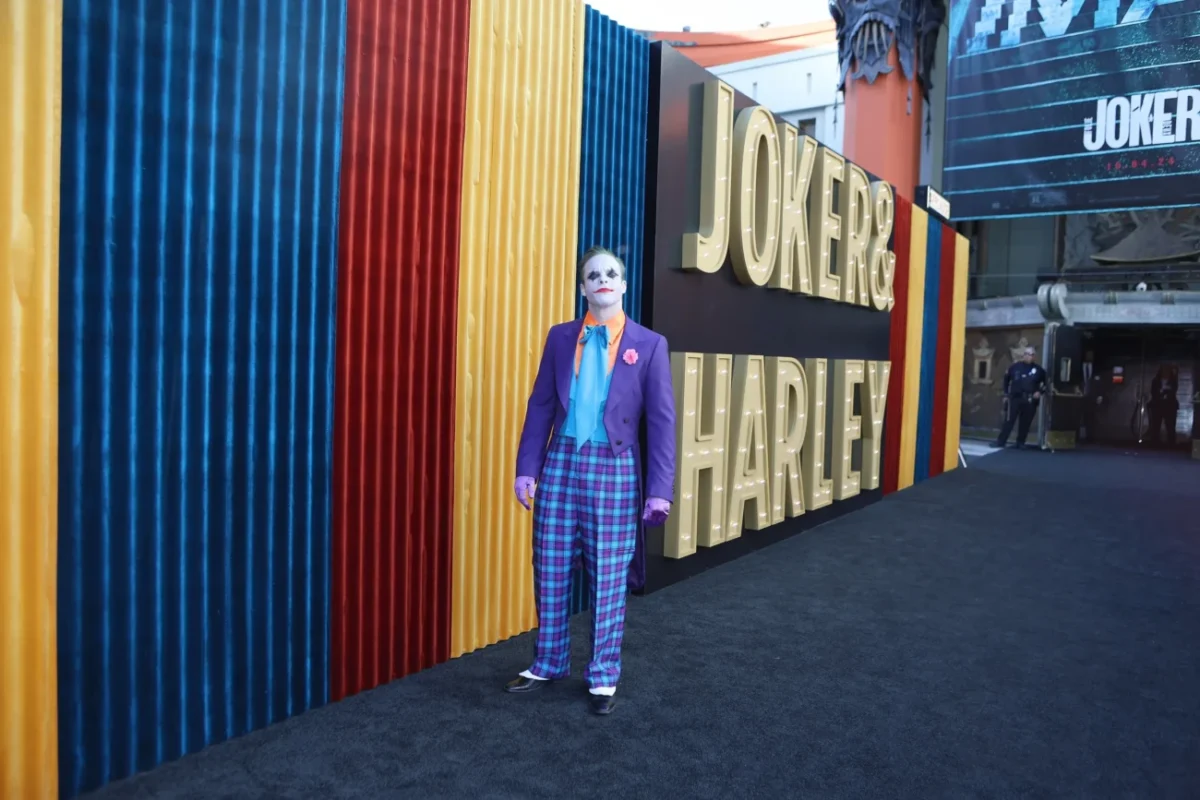 Před nápisem Joker stojí muž za Jokera přestrojený.