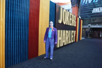 Před nápisem Joker stojí muž za Jokera přestrojený.