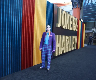 Před nápisem Joker stojí muž za Jokera přestrojený.