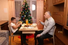 Muž s chlapcem sedí u stolu.