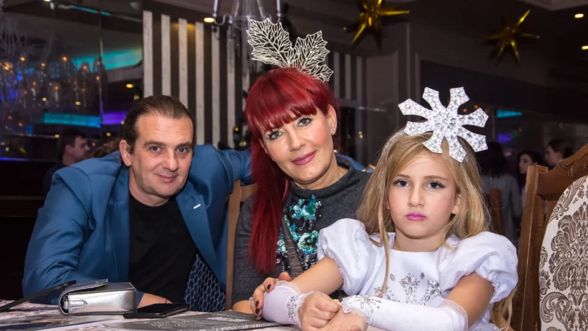 Svátečně oblečená rodina sedí u stolu.