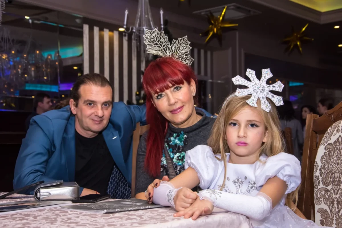 Svátečně oblečená rodina sedí u stolu.