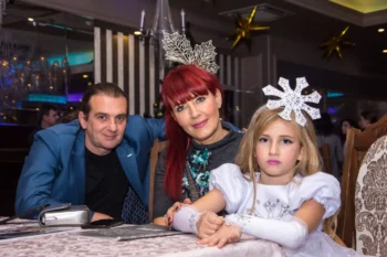 Svátečně oblečená rodina sedí u stolu.