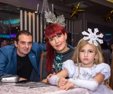 Svátečně oblečená rodina sedí u stolu.