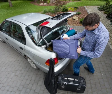 Muž nakládá kufry do auta.