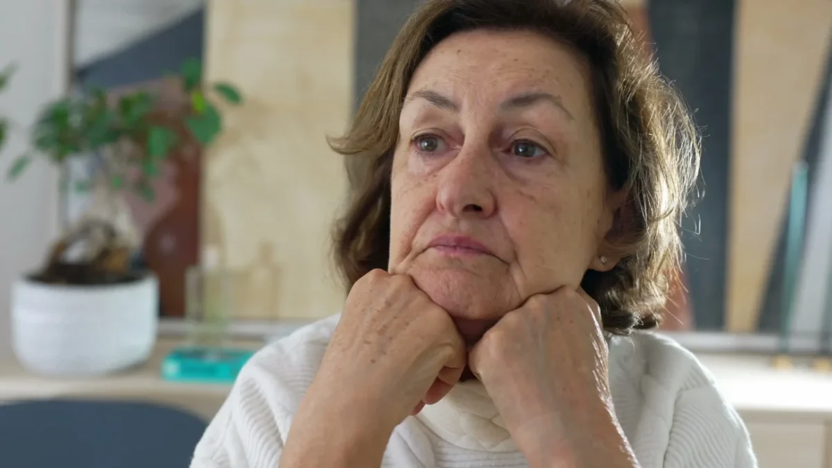 Žena si smutně opírá hlavu o ruce.