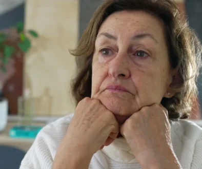 Žena si smutně opírá hlavu o ruce.