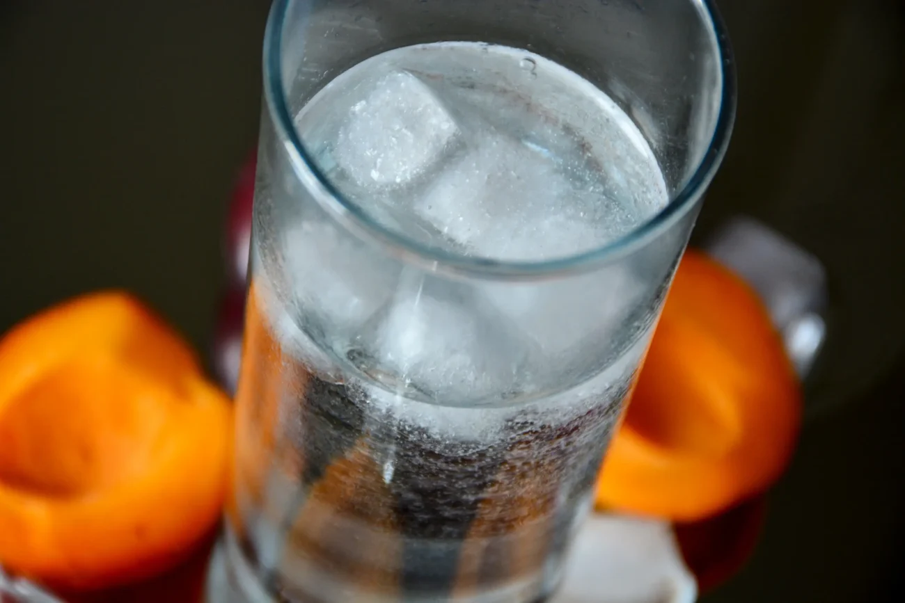 Na stole leží společně s meruňkami sklenička pití.