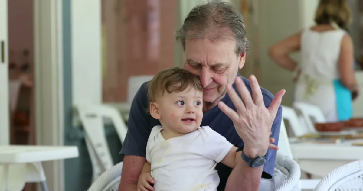 Chlapeček sedí na klíně dědovi.