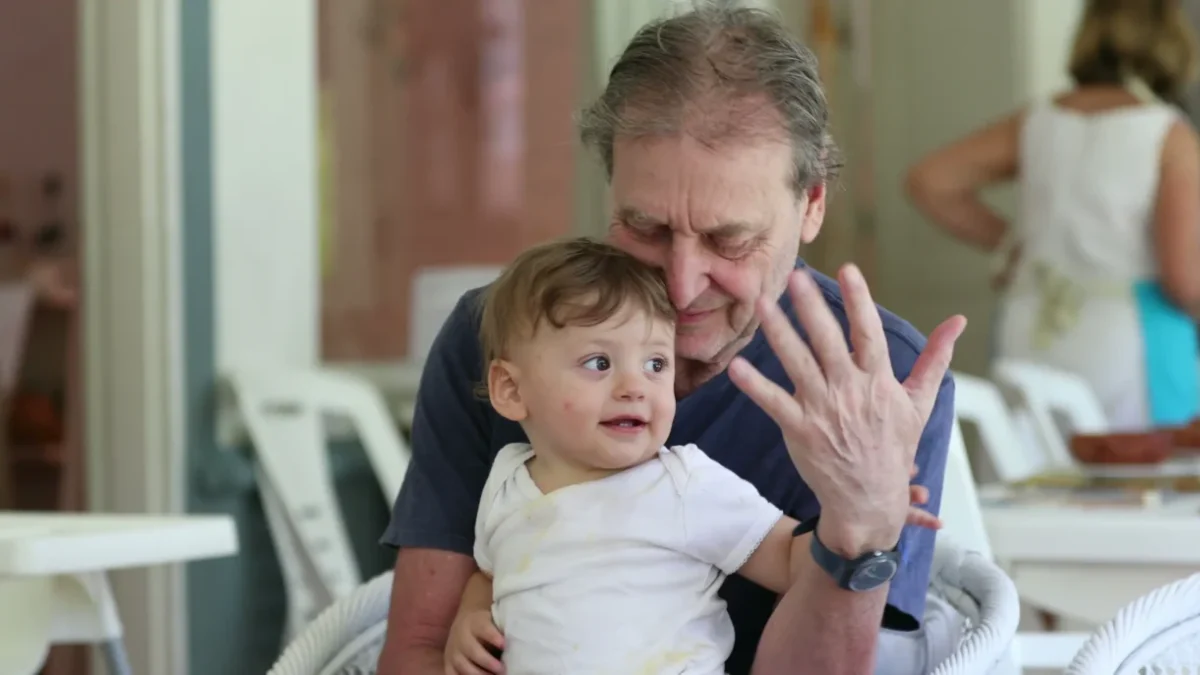 Chlapeček sedí na klíně dědovi.