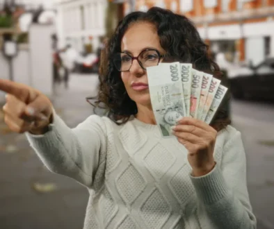 Žena v ruce drží české bankovky.